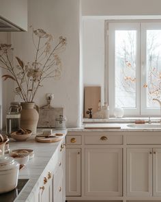 a kitchen filled with lots of white cabinets and counter top space next to a window