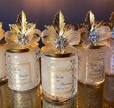 four glass jars with gold leaf decorations on the top and bottom, all lined up in rows