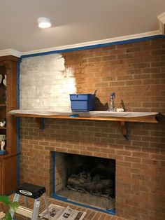 a brick fireplace is being painted with blue tape