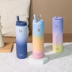 three insulated tumblers sitting on a table next to a pillow and vases