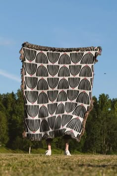 a person standing in the grass with a large blanket