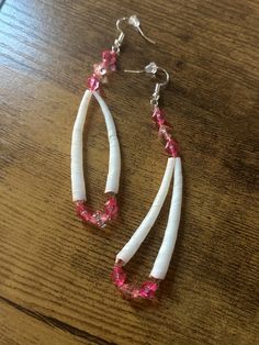 two white and pink earrings on a wooden table