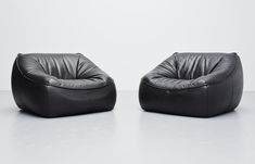 two black leather chairs sitting next to each other on top of a white flooring