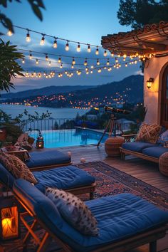 an outdoor living area with lights strung over the water and patio furniture on the deck