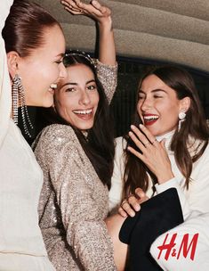 three young women are laughing and posing for the camera