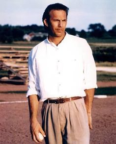 a man standing on top of a dirt field holding a white frisbee in his hand