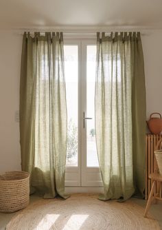 a living room with a large rug and green curtains on the window sill, next to a wicker basket