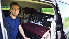 a man sitting in the back of a van with luggage on it's bed