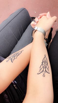 two people holding hands with tattoos on their arms and legs, sitting next to each other