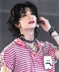 a woman with black hair wearing a pink and white striped shirt holding a cell phone to her ear