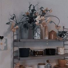 a shelf filled with cups and vases on top of it