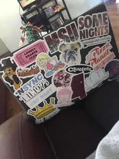 a laptop covered in stickers sitting on top of a couch next to a christmas tree