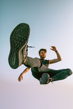 a man flying through the air while riding on top of a skateboard in front of a blue sky