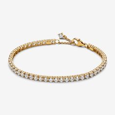 Choose a modern spin on a classic style with the Sparkling Tennis Bracelet. This 14k gold-plated bracelet sparkles with 48 round prong-set stones. Adjustable and dynamic, this cubic zirconia tennis bracelet features one sparkling stone dangling from beside the clasp for the perfect finishing touch. Designed with slightly larger stones than our other tennis bracelet styles, this bracelet is perfect for making a fresh statement when stacked with other bracelets in mixed tones and styles. - Pandora Sparkling Tennis Bracelet - 14k Gold-plated unique metal blend / Cubic Zirconia / Clear - Sz. 7.9 in Pandora Tennis Bracelet Gold, Bracelet Styles, Xmas Wishlist, Bracelet Tennis, Gift Inspo, Monkey Bread, Mum Birthday, Free Bracelet, Birthday List