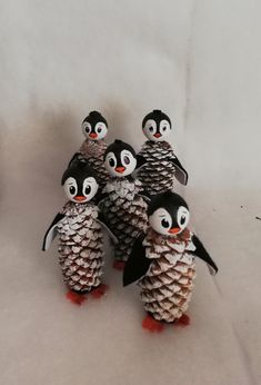 small pine cone penguin figurines are lined up on a white surface with one penguin in the middle