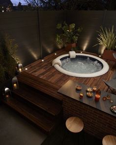 a hot tub sitting on top of a wooden deck next to a table with candles