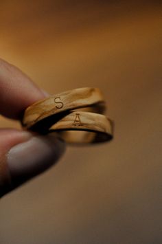 someone is holding two wooden rings with the letter s on them in their left hand