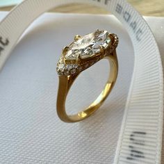 a gold ring with three diamonds on it sitting on top of a white fabric ribbon