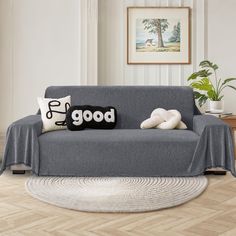 a gray couch with pillows on it in a living room next to a potted plant