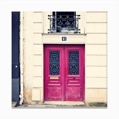 two red doors with wrought iron grills in front of a building