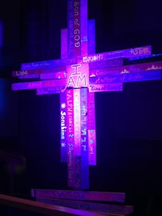 the cross is lit up in pink and purple colors with words all over it that read i am