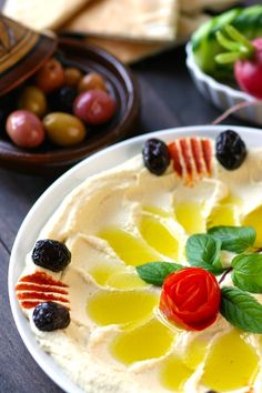 a white plate topped with hummus and olives