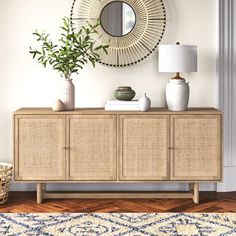 a living room with a rug, mirror and vases on the sideboard in front of it