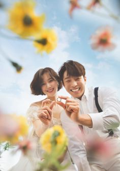 a man and woman are posing for the camera with flowers in front of their faces