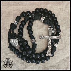 two black beads and a silver cross on a white background