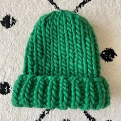 a green knitted hat sitting on top of a white rug