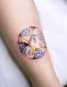 a woman's arm with a tattoo on it that has blue and yellow flowers