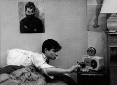 black and white photograph of a woman sitting on a bed with an old fashioned radio