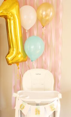 balloons and streamers are hanging from the wall above a baby's crib