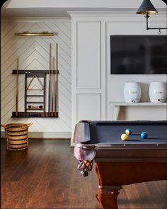 a pool table in a room with white walls and wood flooring on the other side