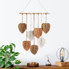 a wooden table topped with a plant next to a wall mounted wind chime hanging from it's side