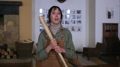 a woman holding a large baseball bat in her hands while standing in a living room