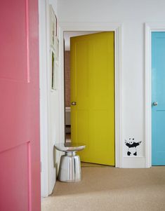 two brightly colored doors in a room with a stool on the floor next to them