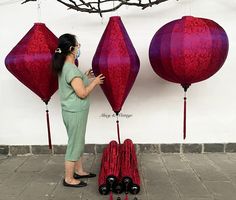 a woman is standing in front of some red lanterns and looking at them with her hands