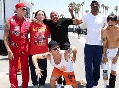 a group of people standing next to each other in front of a white truck and palm trees