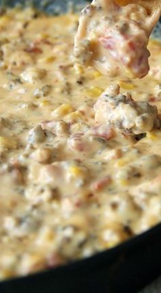 a person dipping some kind of food into a skillet filled with cheese and other toppings