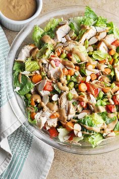 a salad with chicken, lettuce and carrots in a glass bowl on a table