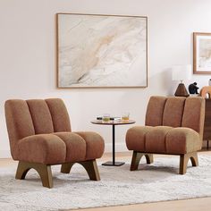 a living room with two chairs and a table in front of a painting on the wall