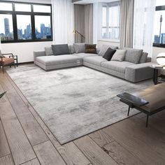 a modern living room with wood floors and large windows in the background, including a gray sectional sofa