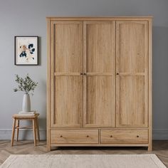 a large wooden armoire in a living room with grey walls and wood flooring