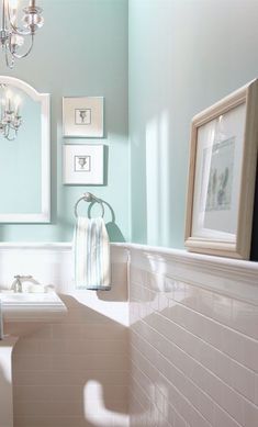 a bathroom with blue walls, white fixtures and a chandelier hanging from the ceiling