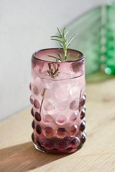 a glass filled with liquid sitting on top of a wooden table next to a plant