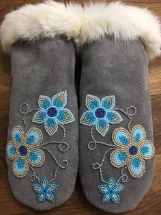 a pair of gray slippers with blue flowers and white fur on the bottom, sitting on a wooden floor