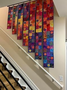 a set of stairs with colorful quilts hanging on the wall