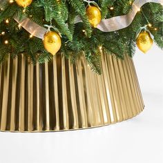 a christmas tree in a gold pot with lights on the top and silver ribbon around it