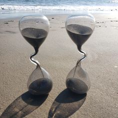 two hourglasses sitting on top of a sandy beach